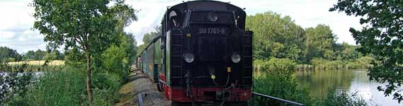 Abbildung: Dampflokomotive mit Personenzug auf der Strecke bei der Querrung des Teiches in Dippeldorf/Sonnenland